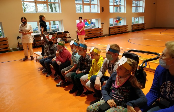 Dzieci na hali sportowej uczą się dbania o zęby i jamę ustną.