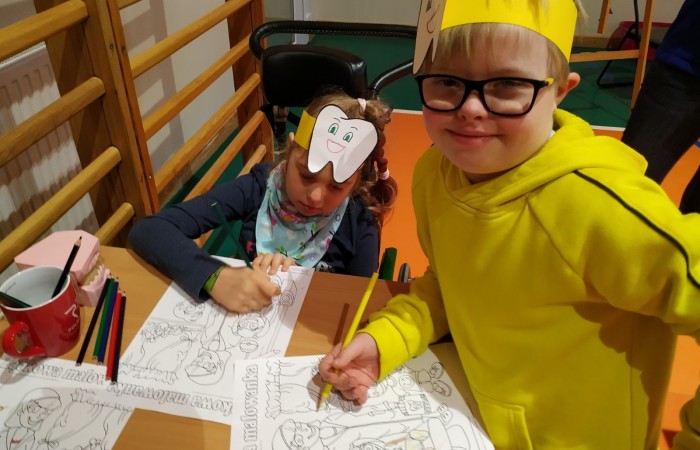 Dzieci na hali sportowej uczą się dbania o zęby i jamę ustną.