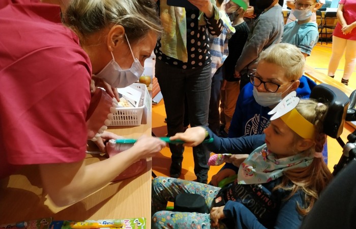 Dzieci na hali sportowej uczą się dbania o zęby i jamę ustną.