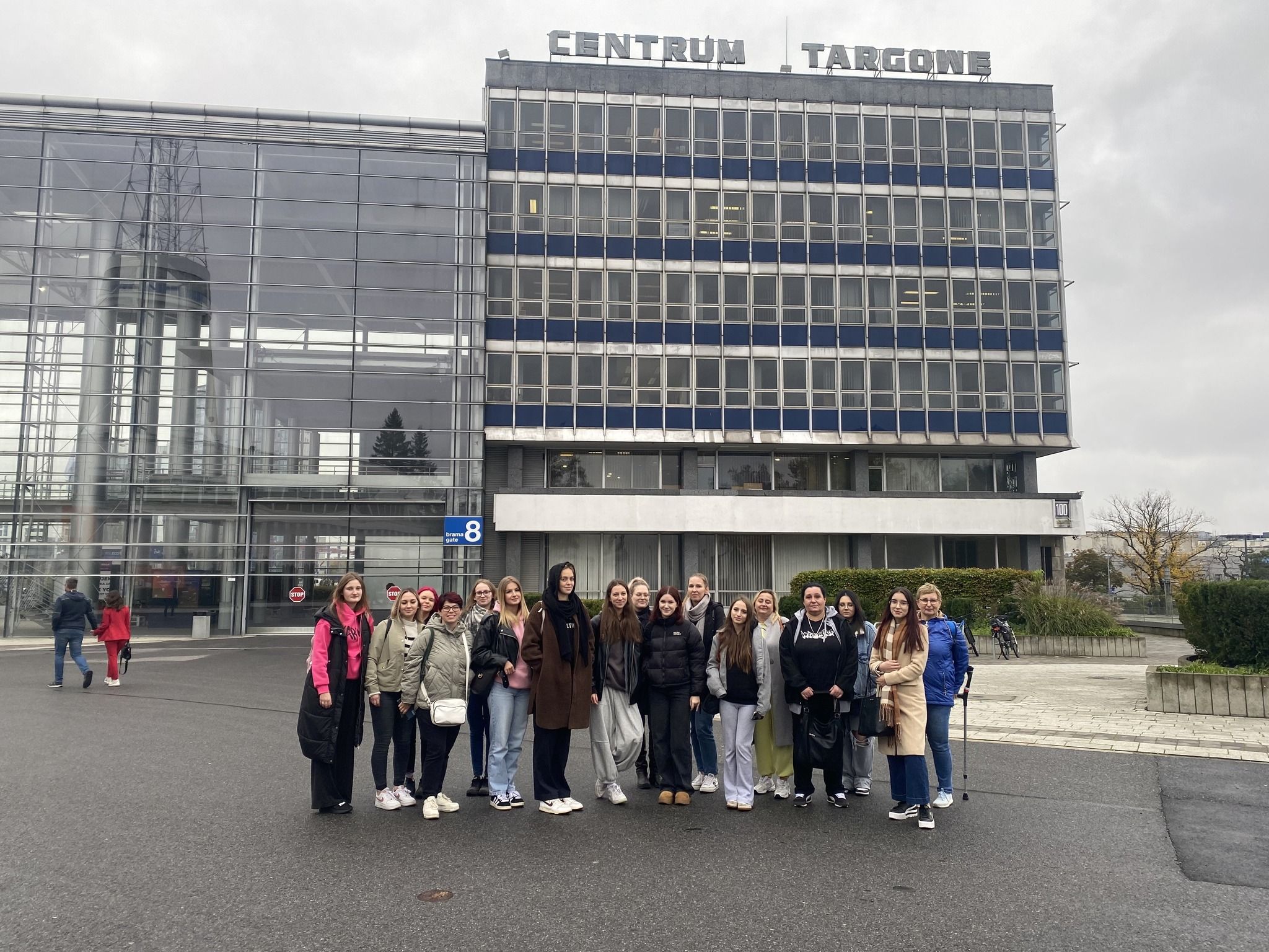 Zdjęcie grupowe z widokiem na budynek centrum targowego.