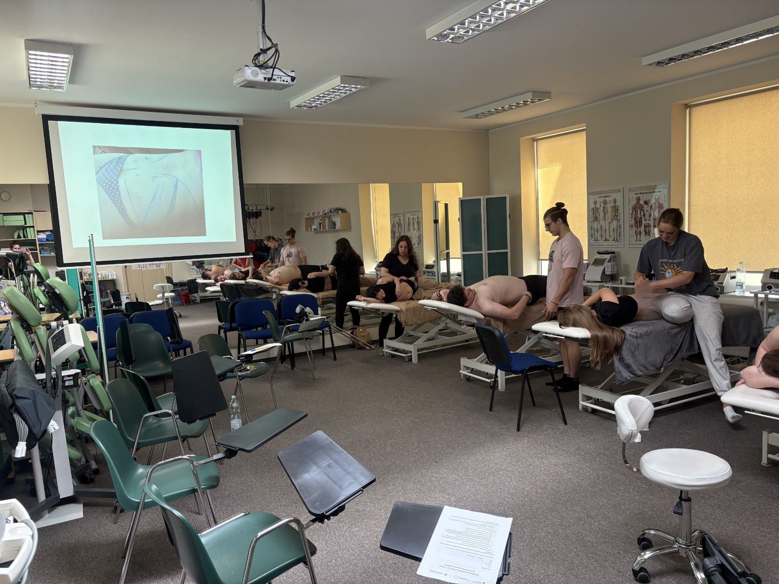 Wspólne zdjęcie uczestników szkolenia. Wykonywanie zdań w sali masażu.