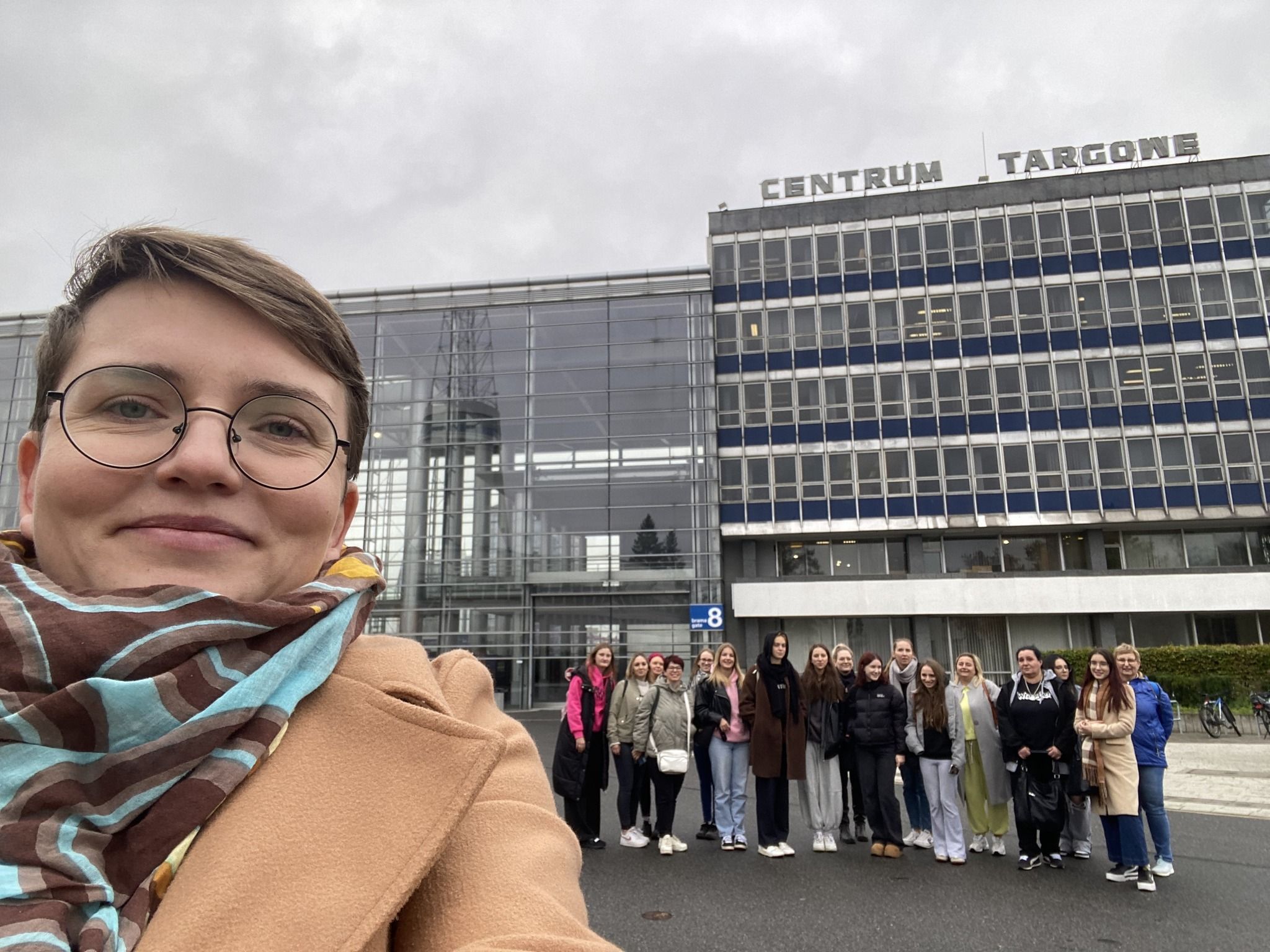 Zdjęcie grupowe z widokiem na budynek Centrum Targowego.