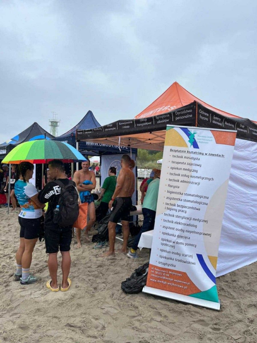 Zdjęcie na namiot z uczestnikami na plaży podczas deszczu.