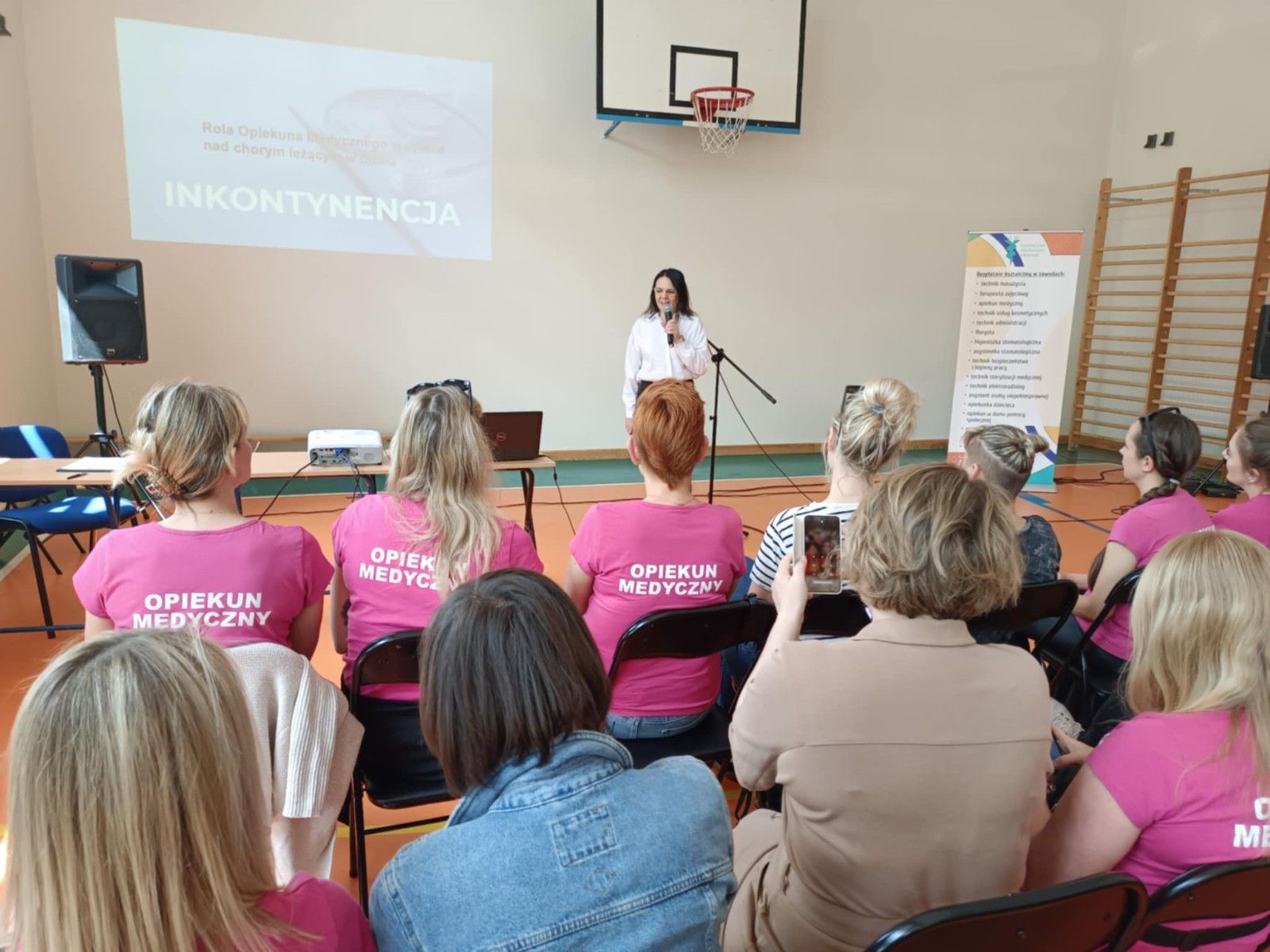 Widok na prowadzącego prezentację wyświetlaną na ścianie.