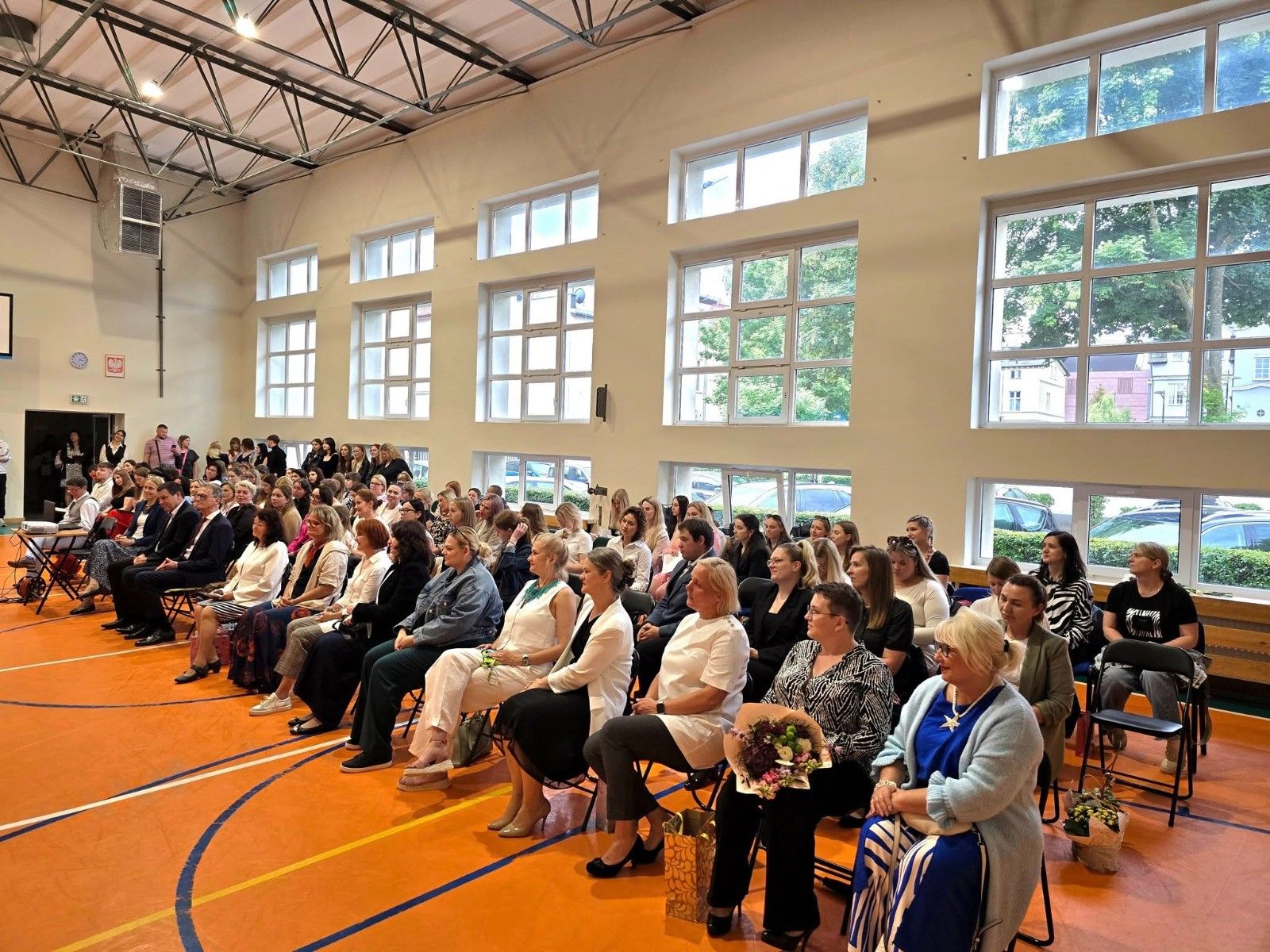 Widok na uczniów  i nauczycieli na hali sportowej podczas uroczystości zakończenia roku szkolnego..