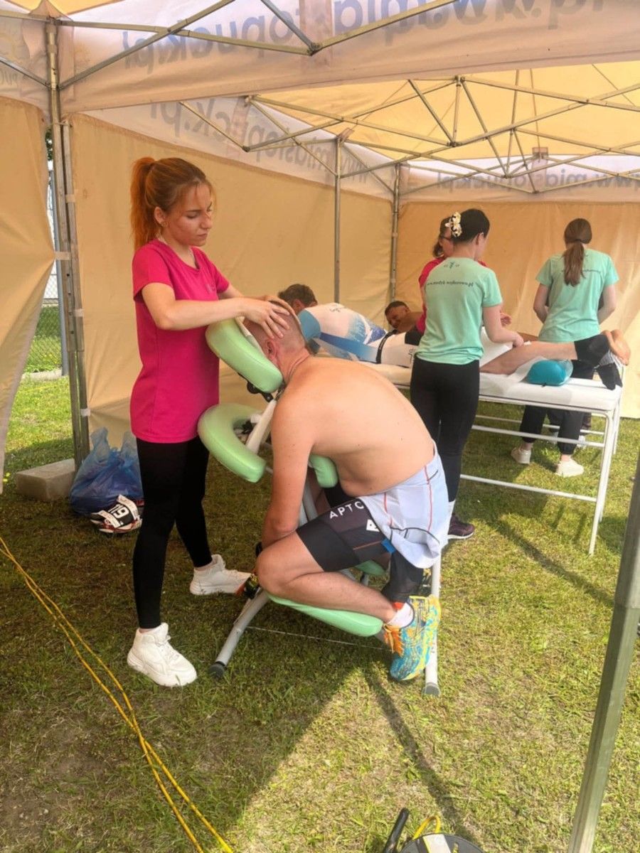 Uczennica wykonująca masarz ramion na specjalnym krześle.
