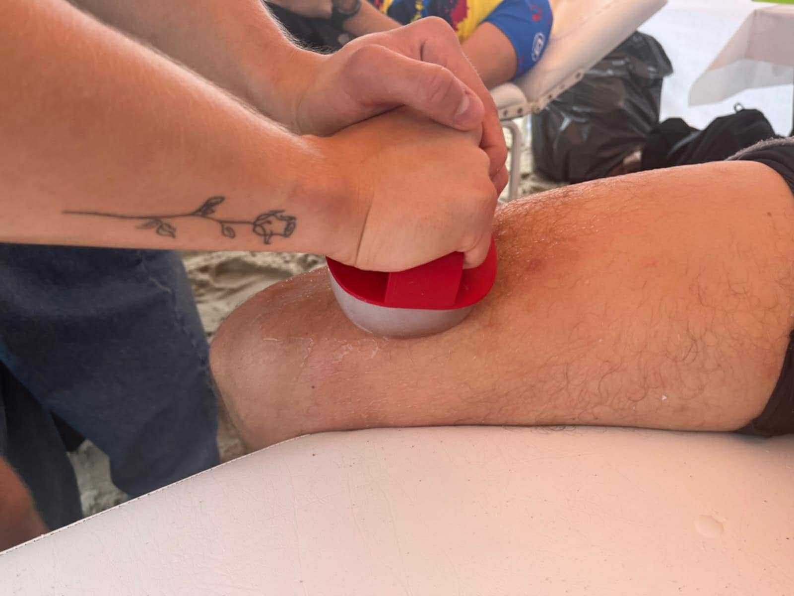 Masaż nogi uczestnika specjalnym przyrządem do masażu.