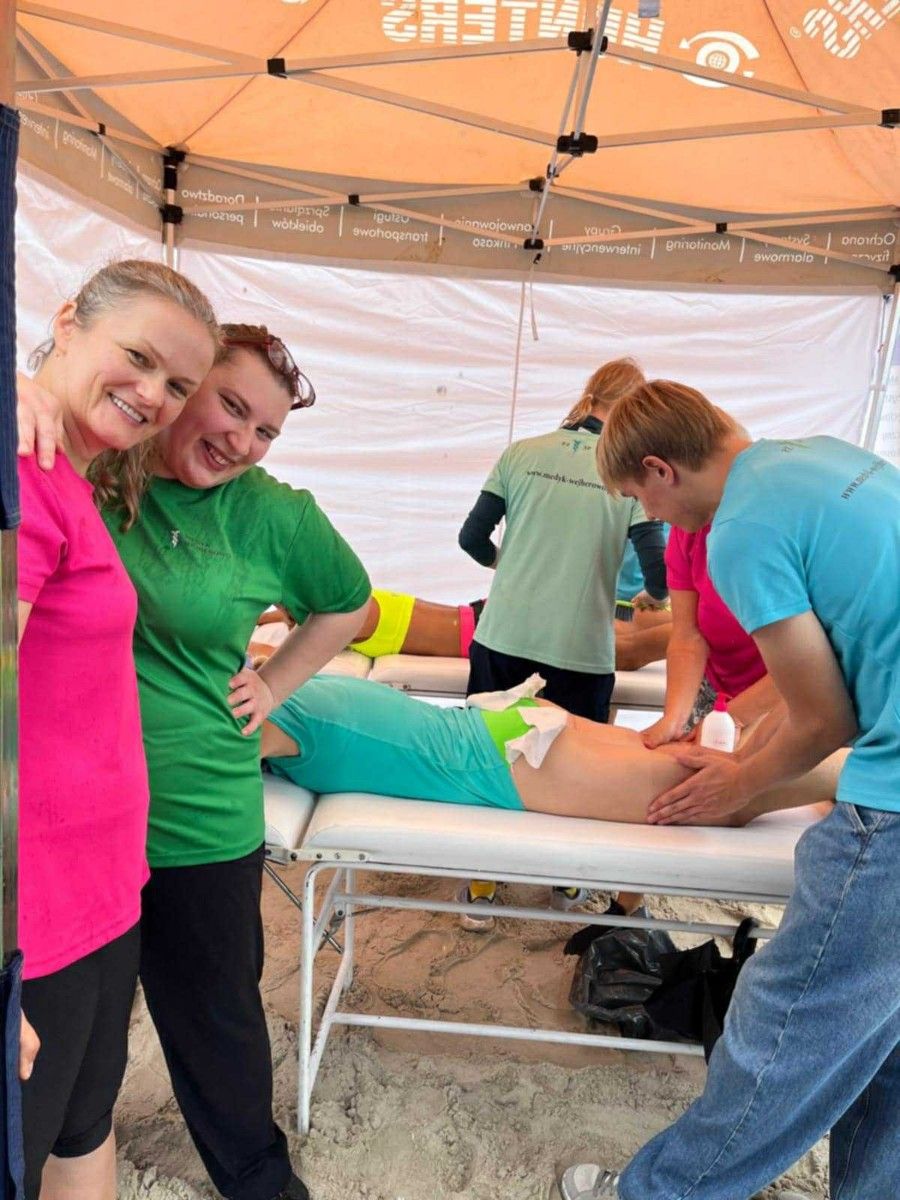 Masaż nóg na stole do masażu przez uczniów uczestnika maratonu.