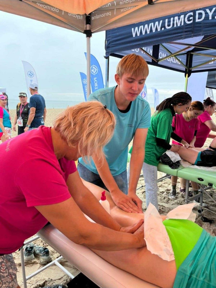 Masaż nóg na stole do masażu przez uczniów uczestnika maratonu.
