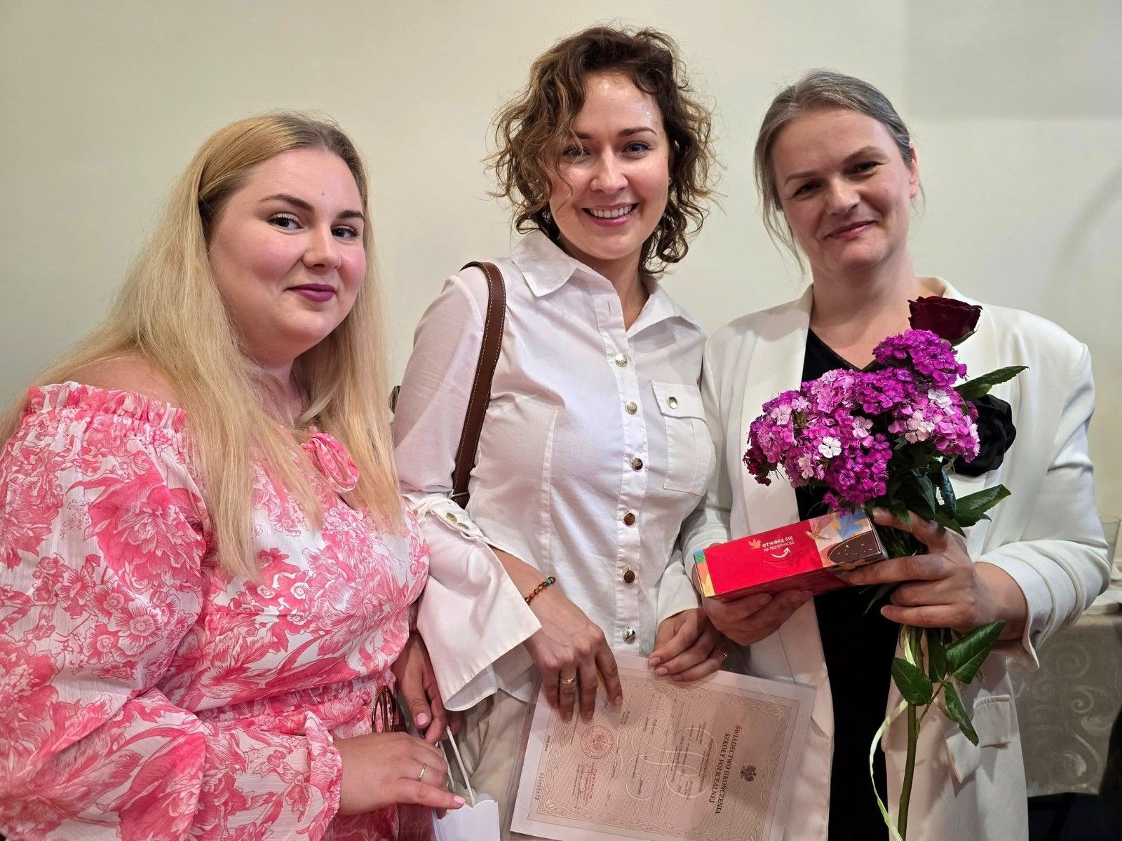 Wspólne zdjęcie uczniów i nauczycieli z kwiatami.