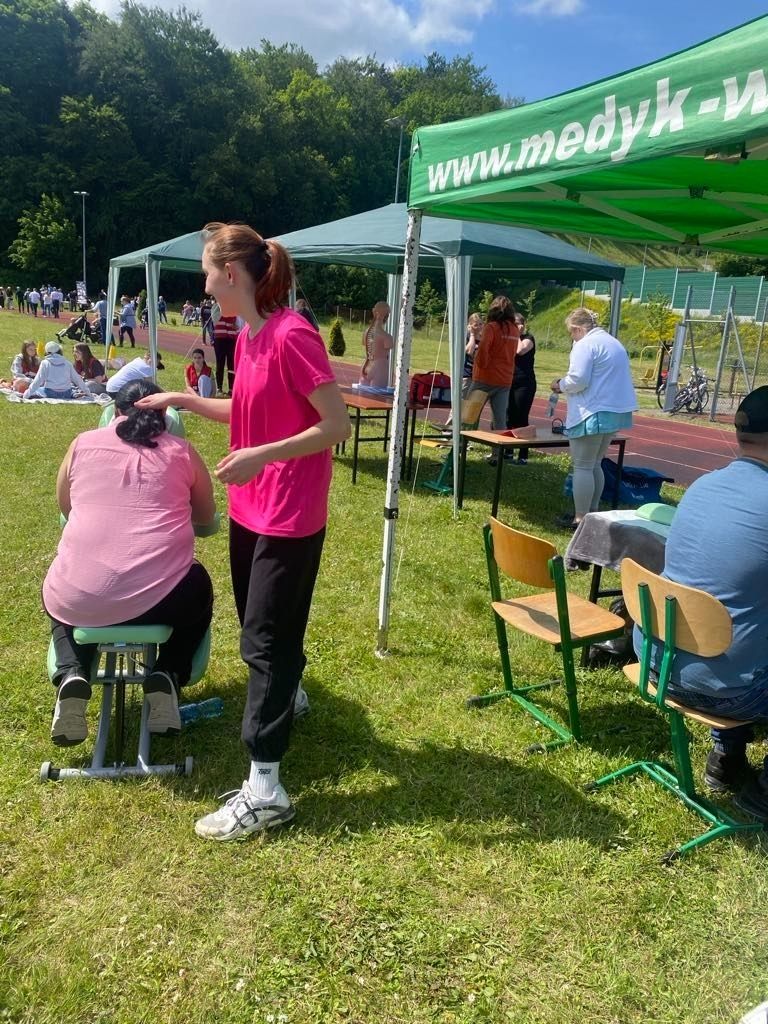 Uczennica wykonująca masarz ramion na specjalnym krześle.