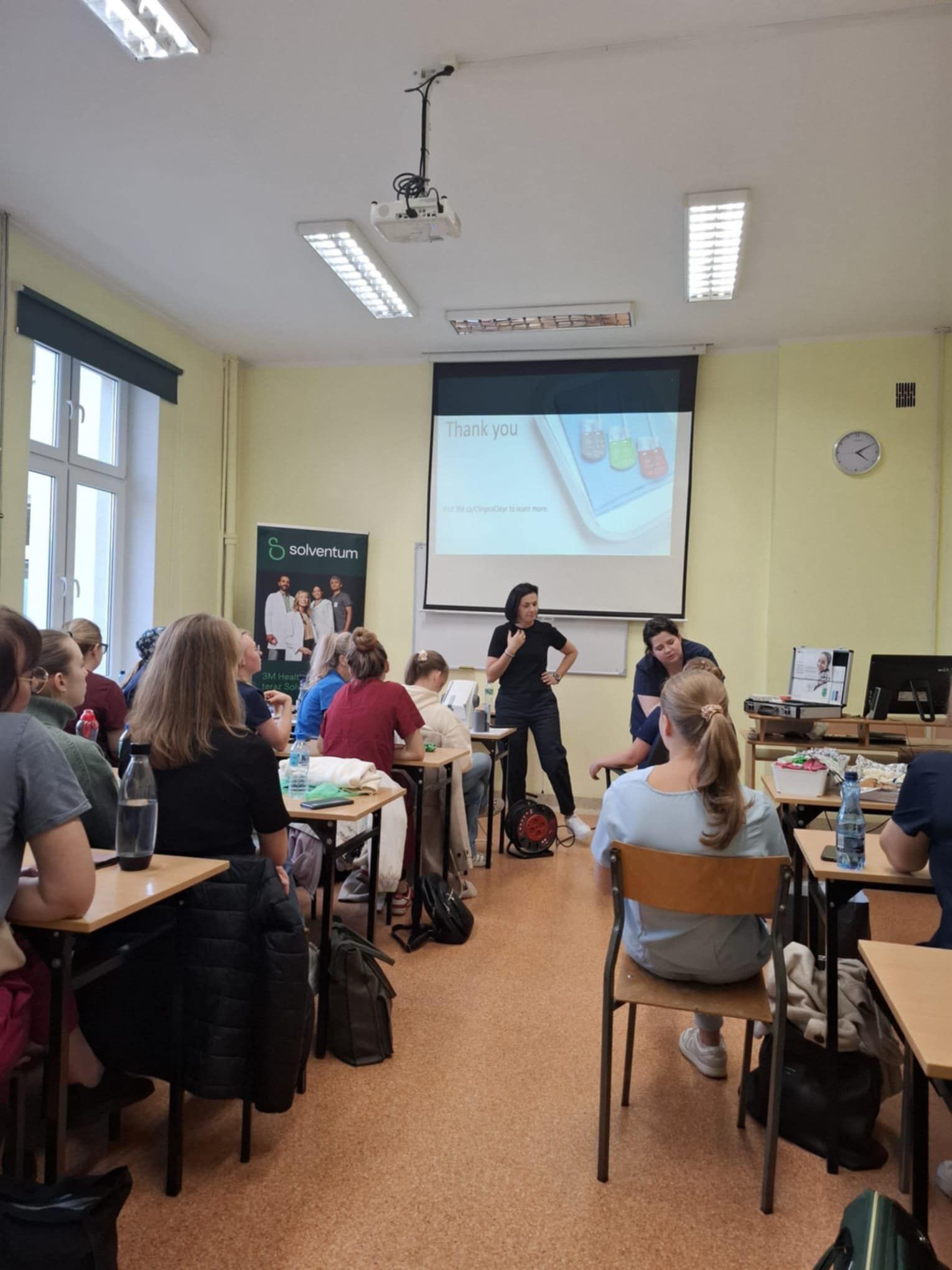 Widok na salę z słuchaczami oglądającymi prezentację.