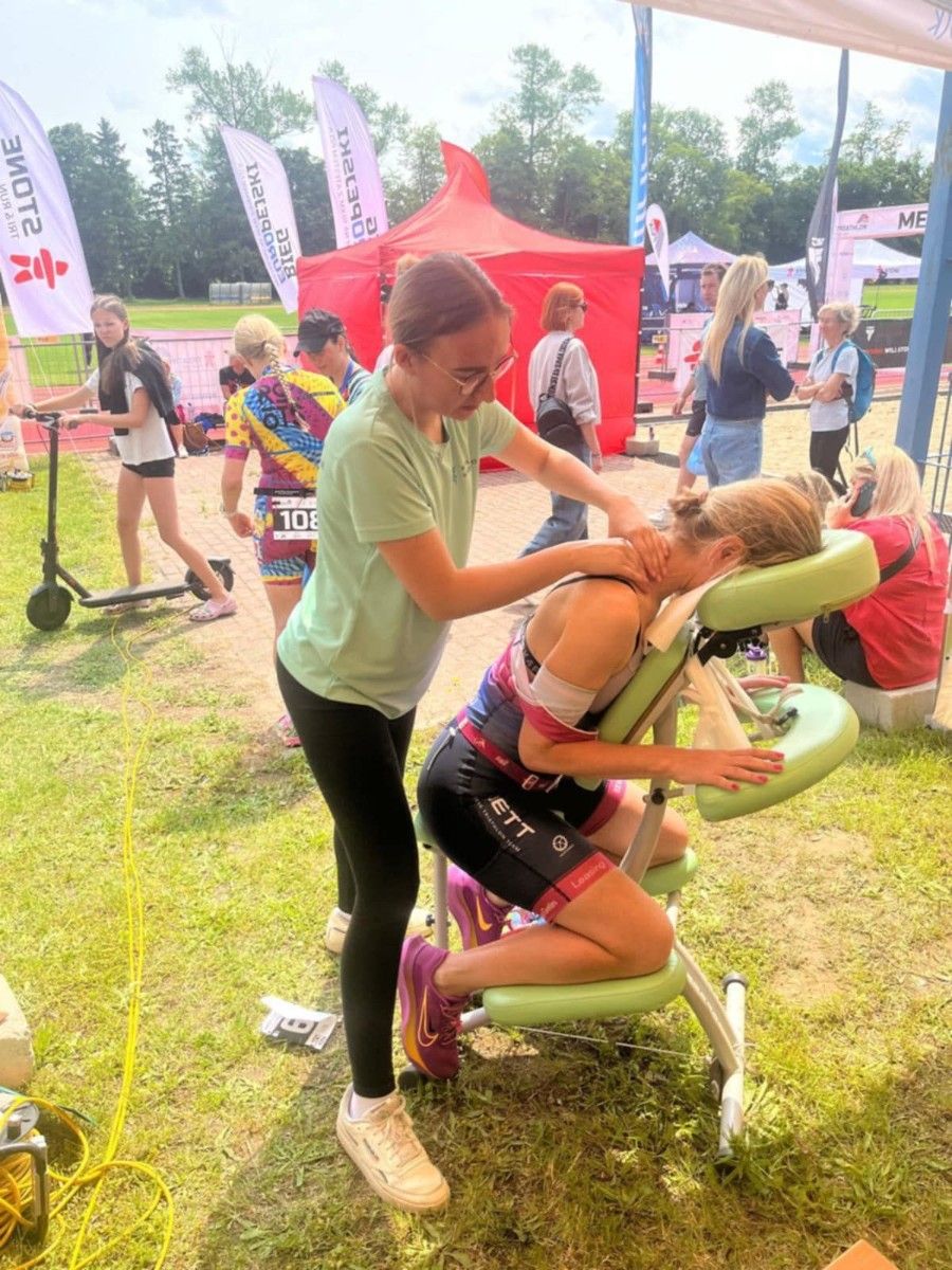 Uczennica wykonująca masarz ramion na specjalnym krześle.